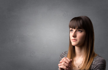 Obraz premium Young woman praying on a grey background