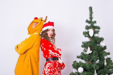 Holiday, humor, people concept - Happy young woman in santa claus hat and man in carnival costume of deer