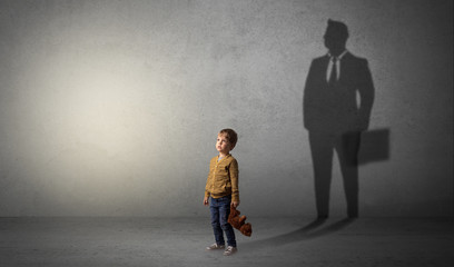 Little boy imagine that he will be businessman and illustrating his future in a big shadow
