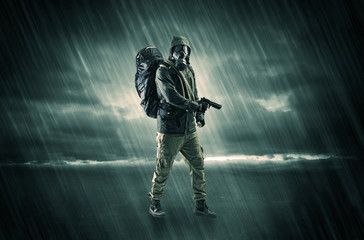 Fototapeta na wymiar Terrorist in a stormy space with gas mask on his hand and weapons on his arm 