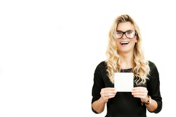 Naklejka premium Surprised emotional beautiful young girl holding a blank advertisement sheet on white isolated background. Black Friday, shopping, discounts