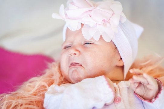 Cute newborn Caucasian baby about to start to cry, funny facial expression with bottom lip lower lip. Sad and upset infant child.