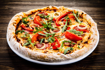 Pizza with pepper,salami and champignon on wooden table