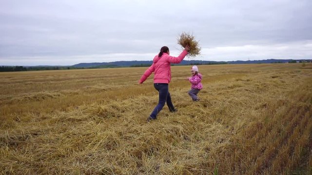 Little girl and mother are playing in the field. Autumn landscape. Stubble.