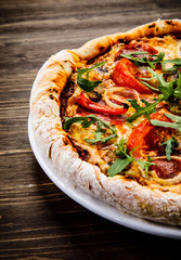 Pizza with pepper,salami and champignon on wooden table