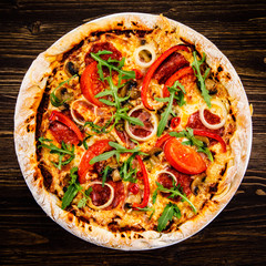 Pizza with pepper,salami and champignon on wooden table