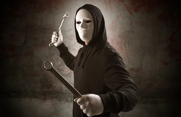 Armed rude assassin in an empty bloody room concept with gun ax chainsaw mallet wrench
