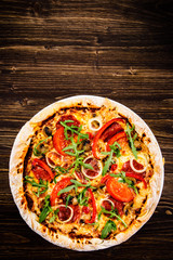 Pizza with pepper,salami and champignon on wooden table