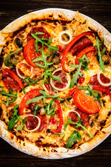 Pizza with pepper,salami and champignon on wooden table