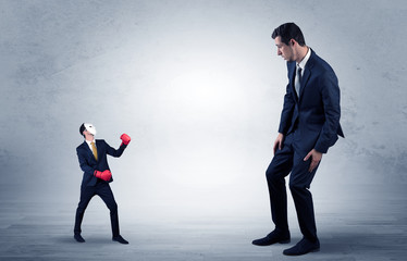 Fototapeta premium Big businessman being afraid of small masked businessman with box gloves in an empty room concept 