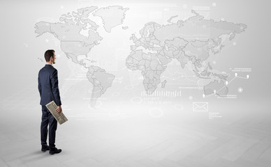 Businessman standing with his back and looking at a worldwide map with objects in his hand
