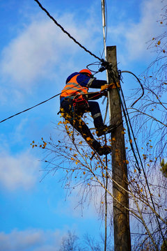 Electrical engineer holding safety helmet with electricians working on electric power pole with bucket hydraulic lifting platform