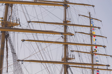 Colorful nautical sailing flags flying in the wind from the lines of a sailboat mast backlit in bright blue sky by the cloudy stormy day. Retro toned.