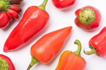 Several ripe sweet and hot peppers of red and orange on a white background