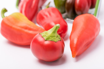 Several ripe sweet and hot peppers of red and orange on a white background