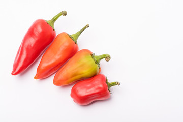 Several ripe sweet and hot peppers of red and orange on a white background