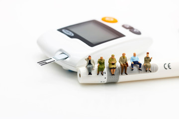 Miniature people sitting on a glucose meter of diabetes , business and health care concept.