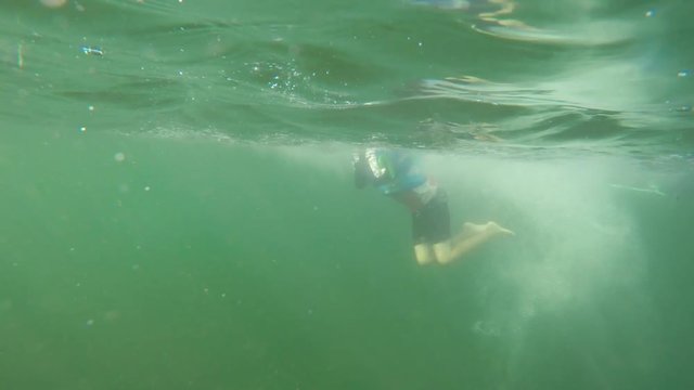 An Underwater Shot Of Boy Jumping From A Dock And Swimming In Ocean
