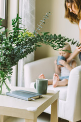 Young mother giving a cup of cocoa to her little son who sits on a sofa
