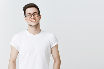 Waist-up shot of pleasant and friendly-looking handsome happy young guy in glasses smiling broadly...