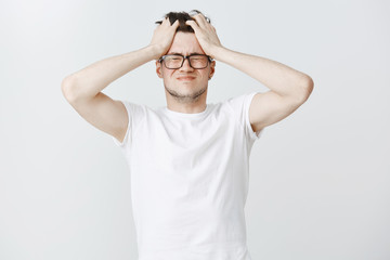 Mind gonna blow-up. Portrait of pressured and distressed upset young male digital nomad holding...