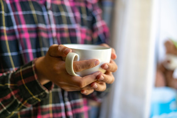 close up hands colding coffee cup in the morning near window f