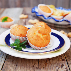 Homemade vanilla muffins in white palte with blue streep. Rustic wooden background. Square image.