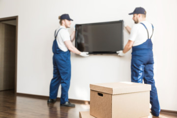 Delivery manremove the TV from the wall for moving to an apartment. professional worker of transportation, male loaders in overalls