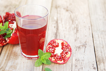 Glass of pomegranate juice and pomegranate fruit on wooden background