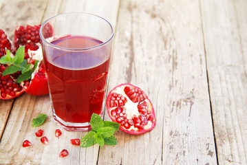 Glass of pomegranate juice and pomegranate fruit on wooden background