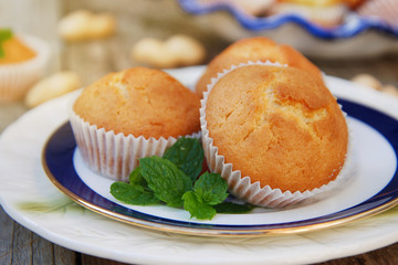Homemade vanilla muffins in white palte with blue streep. Rustic wooden background.