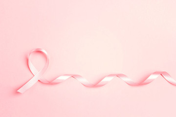 Pink ribbon on pink background with copy space. Breast cancer awareness symbol.