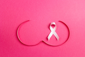 Pink ribbon with breast shape symbol on pink background.
