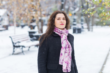 City, winter and people concept - Beautiful happy young woman in black coat and pink scarf in snowy park