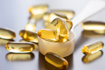 Fish oil capsules on wooden background and texture, vitamin D supplement, selective focus
