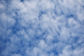 Blue cloudy sky with many white clouds in autumn day as textured background.