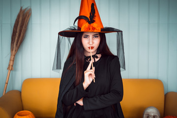 Attractive beautiful Asian woman dressed as a witch holding Magic wand on hand and sitting on...