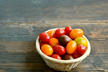 Tomato Varieties ,Type and color mixed together in basket on wooden floor.
A lot kind and different color of tomatoes.