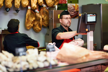 Butcher in a butcher's shop weighing the meat and charging
