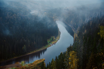 Autumn landscape: fog over the river in the autumn forest, top view. Wilderness.