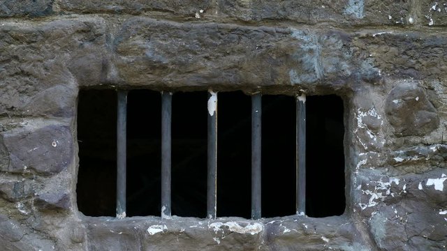 Ancient prison cell window and wall. Metal rods are bricked up in the brickwork.