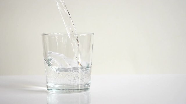 Water pouring into transparent glass. Close up view