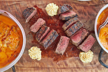 meal of grilled beef steak and pork with sauce in a pan