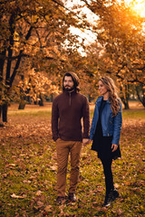 Couple in autumn season colored park enjoying outdoors.