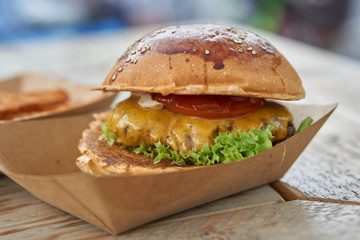 nice cheeseburger and sweet potato fries in paperboard on wooden table