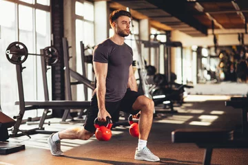 Foto op Plexiglas Handsome man legs workout with kettlebell in the gym © djile