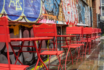 Fototapeta na wymiar Colorful red chairs in the streets of London under a light rain - 3