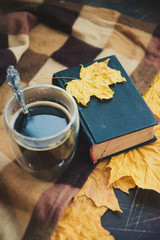 Naklejka na ściany i meble The concept of comfort and warmth in late autumn: coffee in a glass Cup, a blanket and maple Golden leaves.
