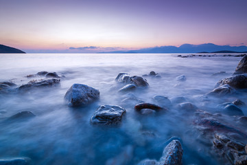 Fototapeta na wymiar Long exposed photo of stones in the water of Mediterranean sea at sunrise. Crete, Greece