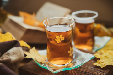 Tea in Turkish cups, books, yellow maple leaves at the window and a warm blanket - the concept of comfort and warmth in autumn.